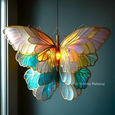 a multicolored butterfly light hanging from a ceiling in a room with blue walls