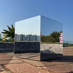 a large mirror sitting on top of a cement block in the middle of a park