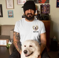 a man sitting in a chair holding a dog and wearing a beanie on his head