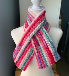 a white mannequin wearing a multicolored knitted scarf