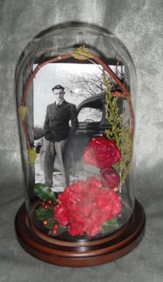 a man standing next to a car under a glass dome filled with flowers and plants