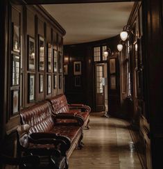 a long hallway with leather couches and framed pictures on the wall