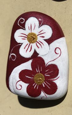 a red and white painted rock with flowers on it