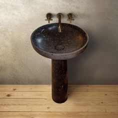 an old fashioned sink on a wooden floor in front of a wall with two faucets