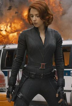 the avengers movie character is standing in front of a large fire and flames behind her