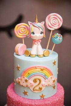 a birthday cake decorated with candy, lollipops and unicorn figurines