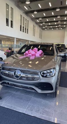 a mercedes car with a pink bow on it's hood in a showroom