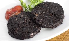 two pieces of brownie on a white plate next to a small piece of tomato