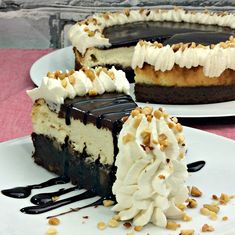 two slices of cheesecake on plates with chocolate sauce and whipped cream