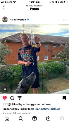 the man is holding up a bottle of beer with his dog on his lap next to him