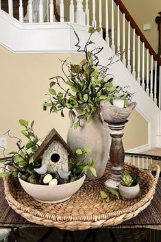 there is a basket with plants in it and a birdhouse on the table next to it