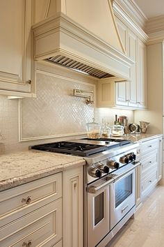 a kitchen with white cabinets and marble counter tops, an oven and stove top in the middle