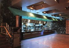 an empty restaurant with marble counter tops and metal ovens on the wall behind it