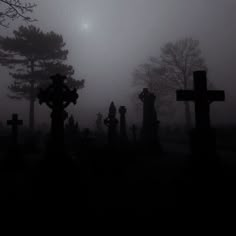 a cemetery in the fog with crosses on it