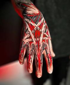 a person's hand with red and black tattoos on it