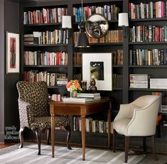 a living room filled with lots of books on top of a book shelf next to a desk