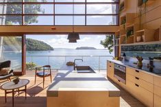 an open kitchen and living room area overlooking the water with large windows on both sides