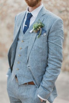 a man with a beard wearing a blue suit and flower boutonniere on his lapel