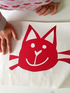 a child's hand on top of a piece of paper with a red cat design