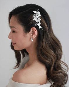 a woman with long hair wearing a white dress and a flower clip in her hair