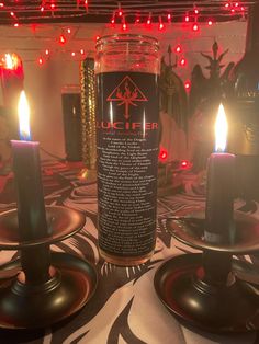 three lit candles sitting on top of a table next to some wine bottles and lights