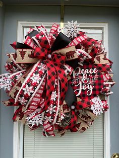 a red and black christmas wreath hanging on a door with the words peace love joy