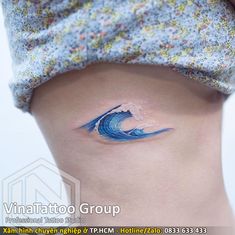 a woman's stomach with a blue wave tattoo on it