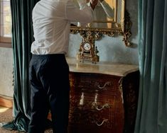 a man is fixing his tie in front of a mirror