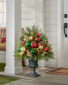 a vase filled with christmas ornaments on the front porch