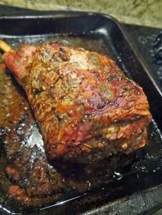 a piece of meat is being cooked in a pan with a wooden spoon on the side