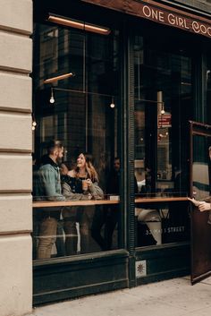 a man and woman standing in front of a restaurant window