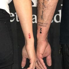 two people holding hands with tattoos on their arms