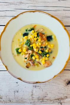 a white bowl filled with corn and broccoli on top of a wooden table