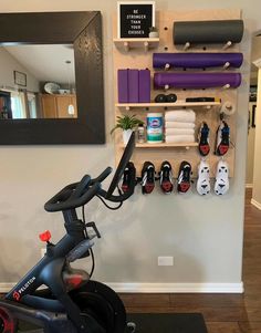 an exercise bike in front of a mirror and shelves with personal items on it's wall