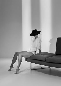 a black and white photo of a woman sitting on a couch with her legs crossed