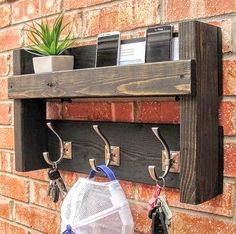 a wooden shelf with two hooks holding keys and other items hanging from it's sides