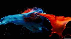 an image of colorful paint splashing on black background