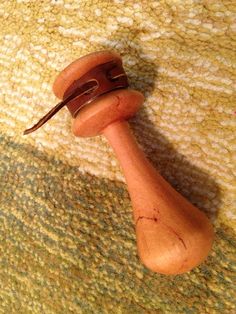 a small wooden object on the floor with a brown cord sticking out of it's end