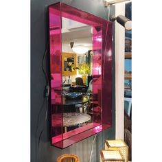 a pink mirror hanging on the wall in front of a chair and other furniture items