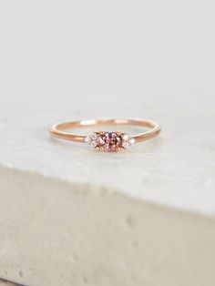 a pink diamond ring sitting on top of a stone