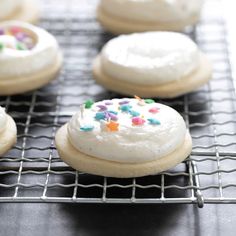 cookies with white frosting and sprinkles on a cooling rack