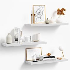 two white shelves with books and vases on them