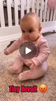 a baby is sitting on the floor and playing with a button in her mouth,