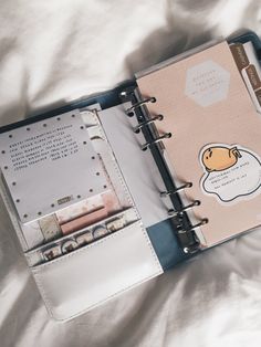 an open planner book sitting on top of a bed