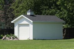 a small white shed sitting on top of a lush green field