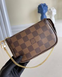 The Mini Pochette Accessoires in Damier Ebene canvas is the perfect way to carry essentials. Its supple, rounded shape gives this pouch a particularly pleasant feel, while its zipped compartment offers a surprising amount of space. It can be hand-carried or attached to a larger bag thanks to the gold-tone chain and hook. Detailed Features 15.5 x 10.5 x 4 cm (Length x height x width ) Damier Ebene coated canvas Cowhide-leather trim Textile lining Gold-color hardware Chain with hook Zip closure Ch Mini Pochette Accessories, Louis Vuitton Mini Pochette, Pochette Accessories, Louis Vuitton Mini, Accessories Bag, Damier Ebene, Vuitton Bag, Large Bag, Wallet Case