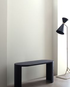 a black table sitting in front of a white wall next to a lamp and floor lamp