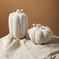 two white pumpkins sitting on top of a bed