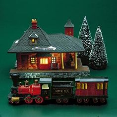 a toy train is sitting in front of a building with christmas decorations on the roof