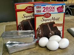 two boxes of cake mix and three eggs on a counter top next to a calculator